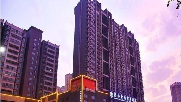 Ein Hochhaus mit mehreren Stockwerken, das durch beleuchtete Schilder und einen markanten Eingang gekennzeichnet ist.