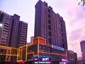 Un edificio de gran altura con varios pisos, con señalización iluminada y una entrada destacada.