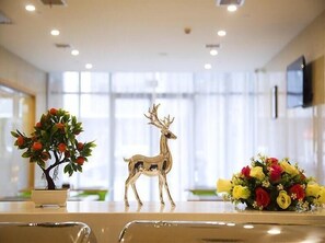 Una habitación con una mesa que presenta una planta en maceta, una figurita de ciervo dorado y un ramo de flores.