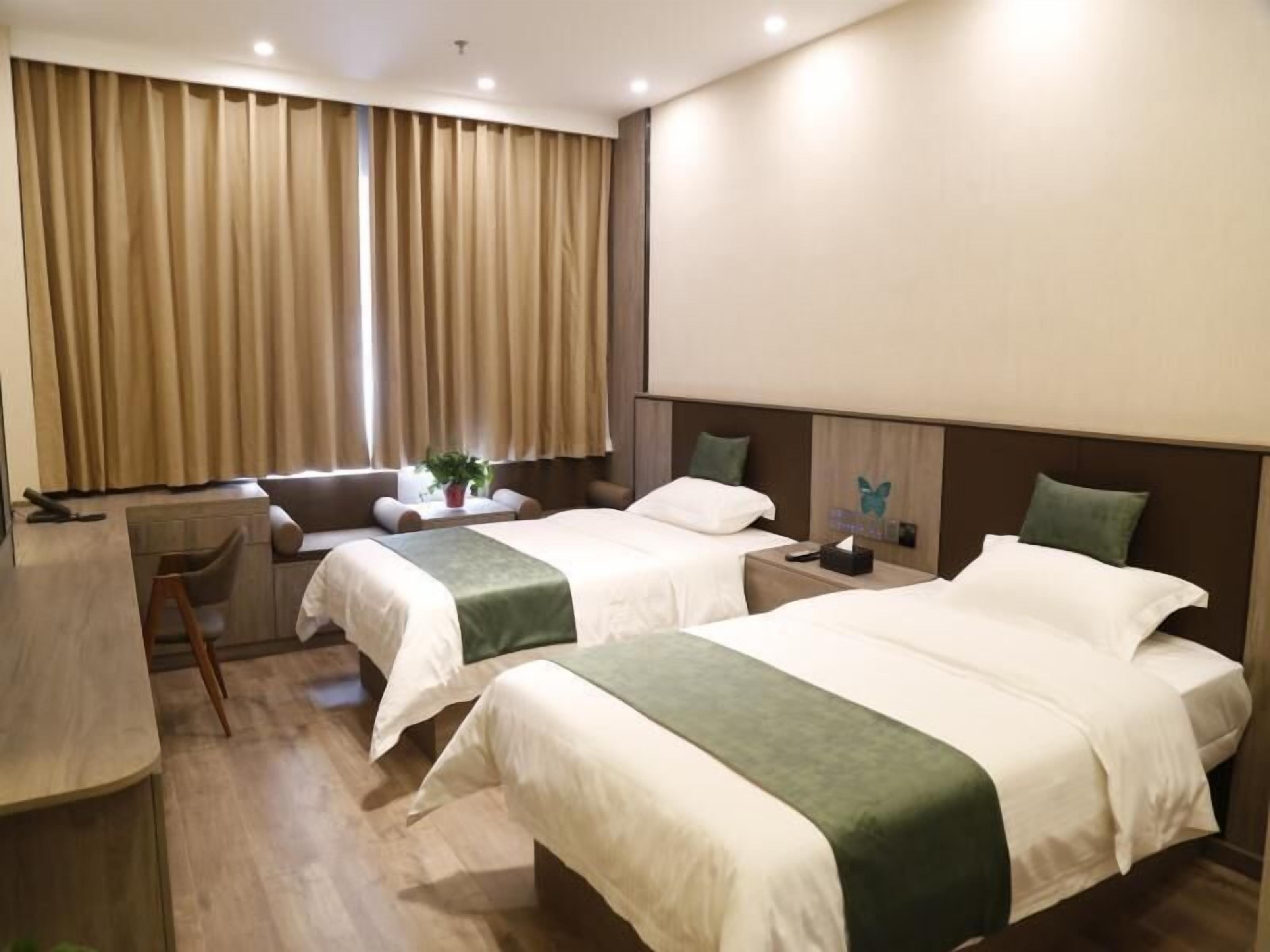 A hotel room with two beds, a desk, and a chair.