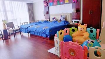Ein Hotelzimmer mit Bett, Schreibtisch und Stuhl. Auf dem Bett liegen bunte Spielsachen und ein Teddybär.