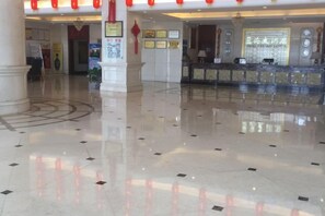 A hotel lobby with a polished floor, reception desk, and decorative columns. - Blue Ocean Hotel (Luannan)