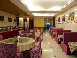 Un restaurante con mesas y sillas redondas, una barra alargada y un pasillo que lleva a otra zona.