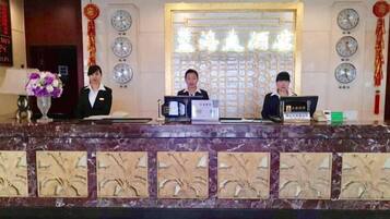 A reception desk with three staff members, a clock, and a decorative wall.
