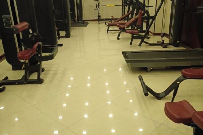 A gym with exercise equipment, a treadmill, and a bench.