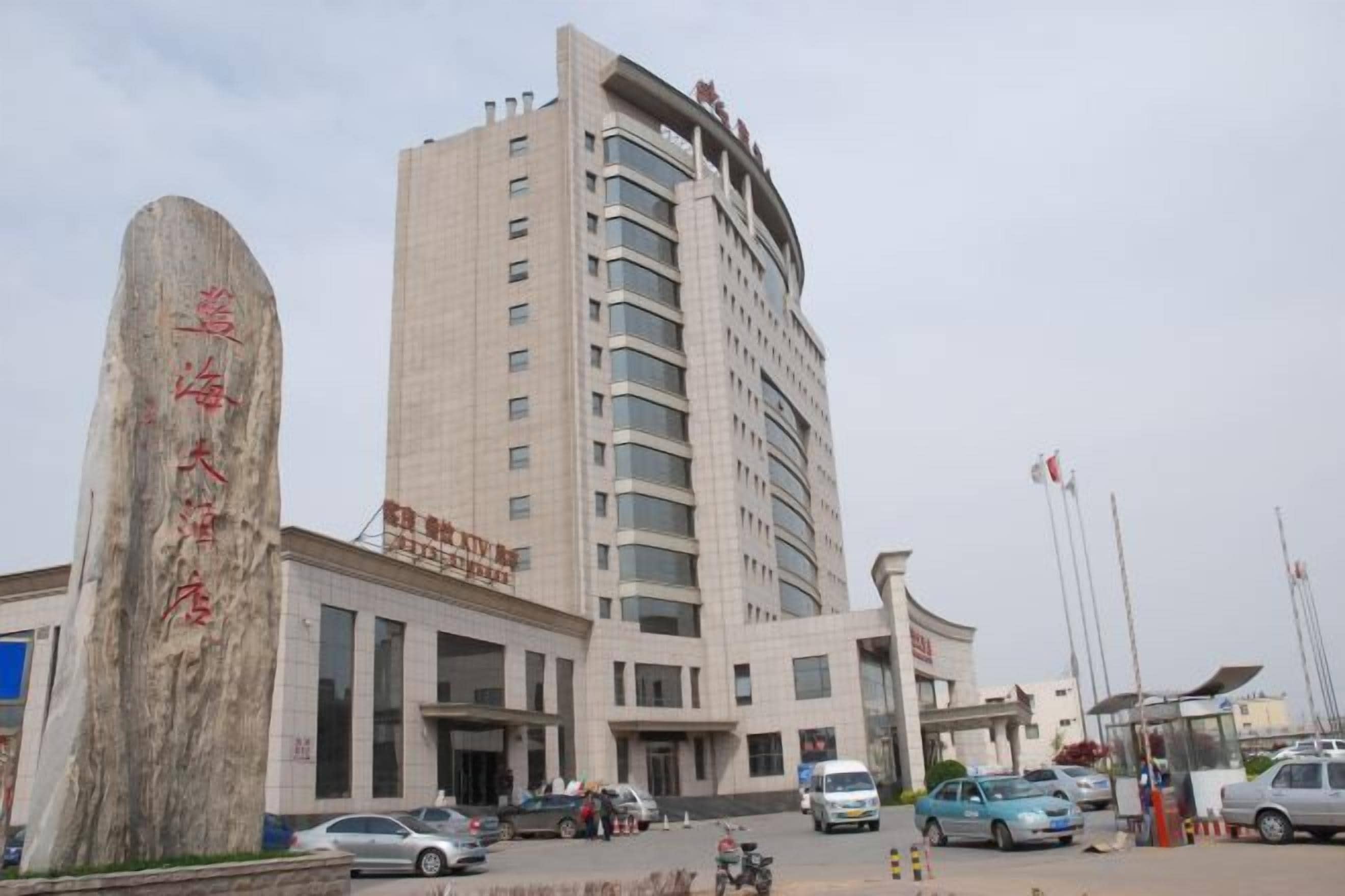 A multi-story building with a prominent entrance and a large stone monument.
