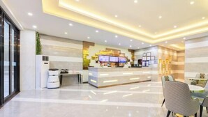 A modern hotel lobby with a reception desk, seating area, and a large window. - GreenTree Inn (Qionghai Boao High-speed Railway Station) (Qionghai)