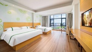A hotel room with two beds, a wooden floor, a large window with a city view, and a dining area with a table and chairs. - GreenTree Inn (Qionghai Boao High-speed Railway Station) (Qionghai)