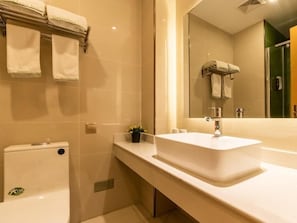 A modern bathroom with a white sink, a mirror, and a toilet.