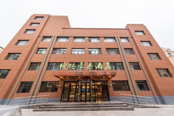 A multi-story building with a prominent entrance featuring a glass door and a staircase leading up to it.