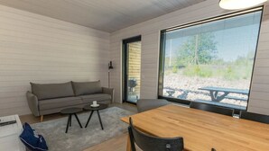 A modern living room with a sofa, a small round table, a wooden dining table, and a large window with blinds. - Kasnäs marina b11 by Interhome (Kemiönsaari)
