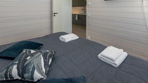 A bedroom with a bed, pillows, a flat-screen TV mounted on the wall, and a door leading to a bathroom. - Kasnäs marina b11 by Interhome (Kemiönsaari)
