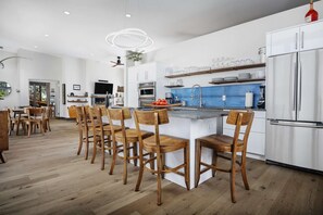 A modern kitchen with a central island, wooden chairs, and a built-in refrigerator. - Modern Custom Vineyard Cottage, Epic Views, Huge Decks, BBQ, Ping Pong, EV Charger, Walk to Wineries (Dundee)