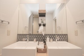A bathroom with two sinks, a large mirror, and a decorative wall tile backsplash. - Family Cottage Yakuin Minami (Fukuoka)