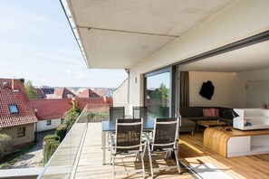 Un appartement moderne doté d’un balcon, d’un coin repas et d’un salon avec un canapé et une table basse.