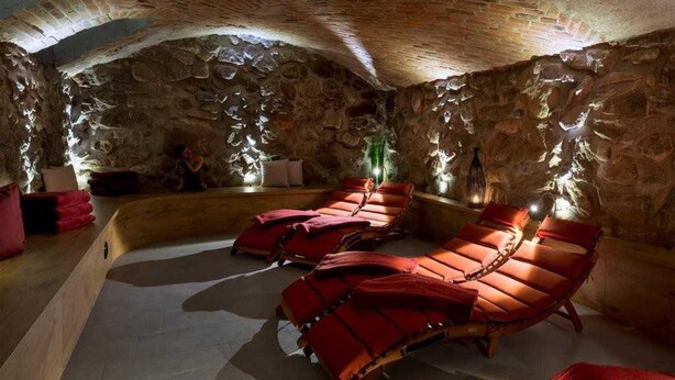 A spa room with stone walls and red lounge chairs.
