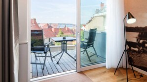Una habitación con puerta corrediza de vidrio que da a una terraza exterior con mesa y sillas.