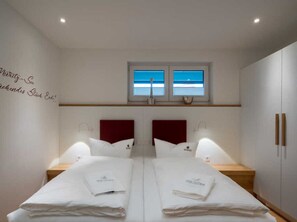Habitación doble con dos camas, una ventana con vistas y una pared con texto.