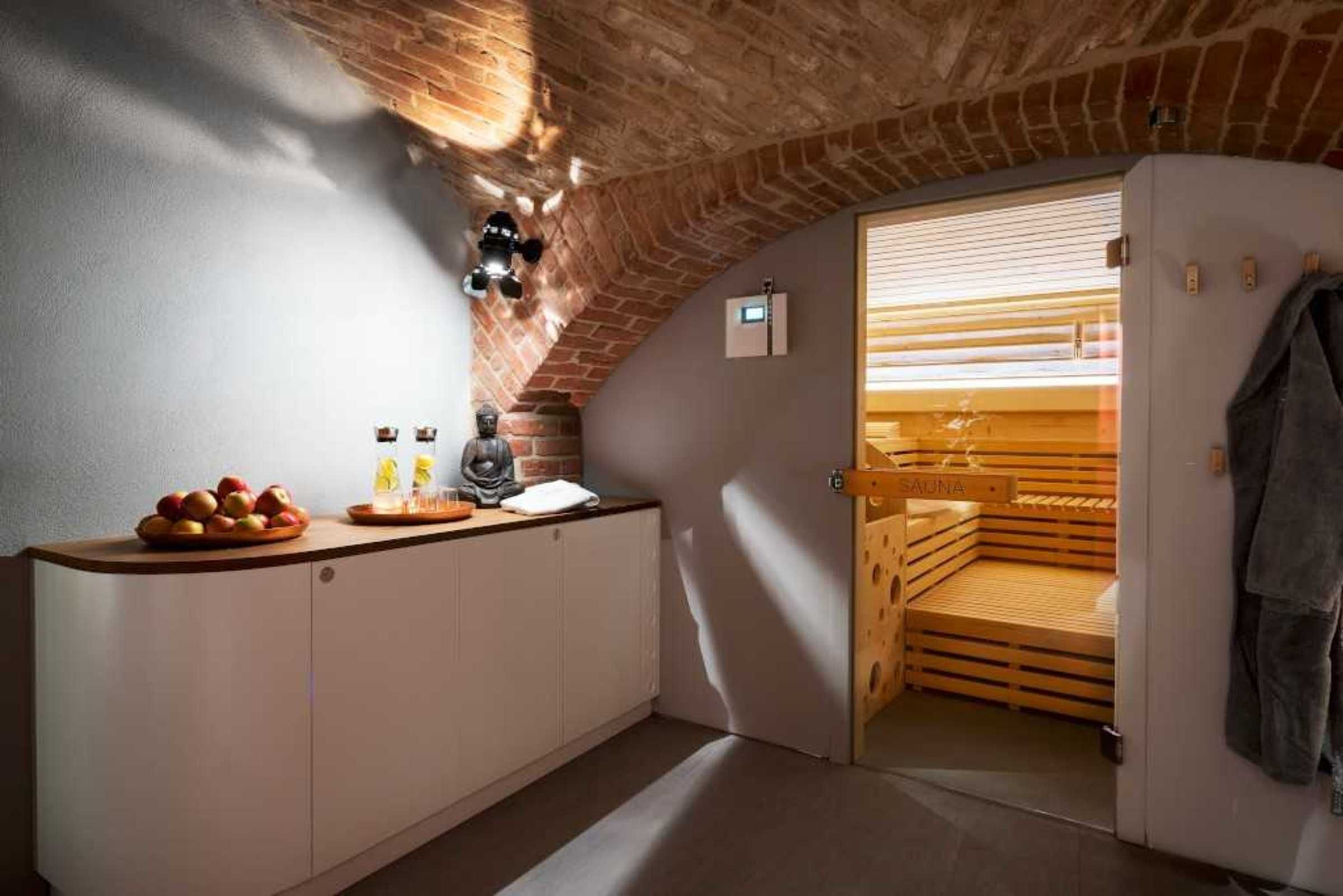 Une petite pièce agréable et chaleureuse, avec un plafond en briques, un sauna et une kitchenette équipée d’un panier de fruits et de bouteilles.