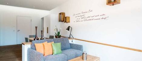 A modern living room with a grey sofa, wooden coffee table, and a wall-mounted light fixture.