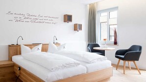 Een moderne hotelkamer met een houten bed, nachtkastjes, een bureau en een stoel.