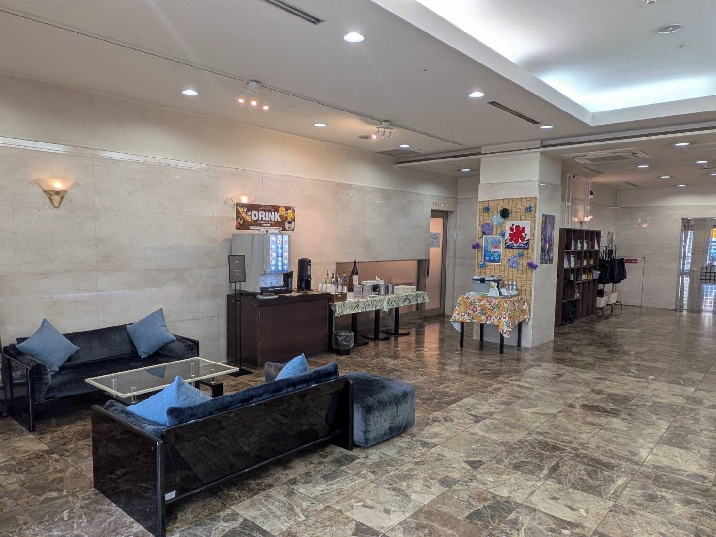 Un hall de hotel con mostrador de recepción, zona de estar y una pared decorada con obras de arte.