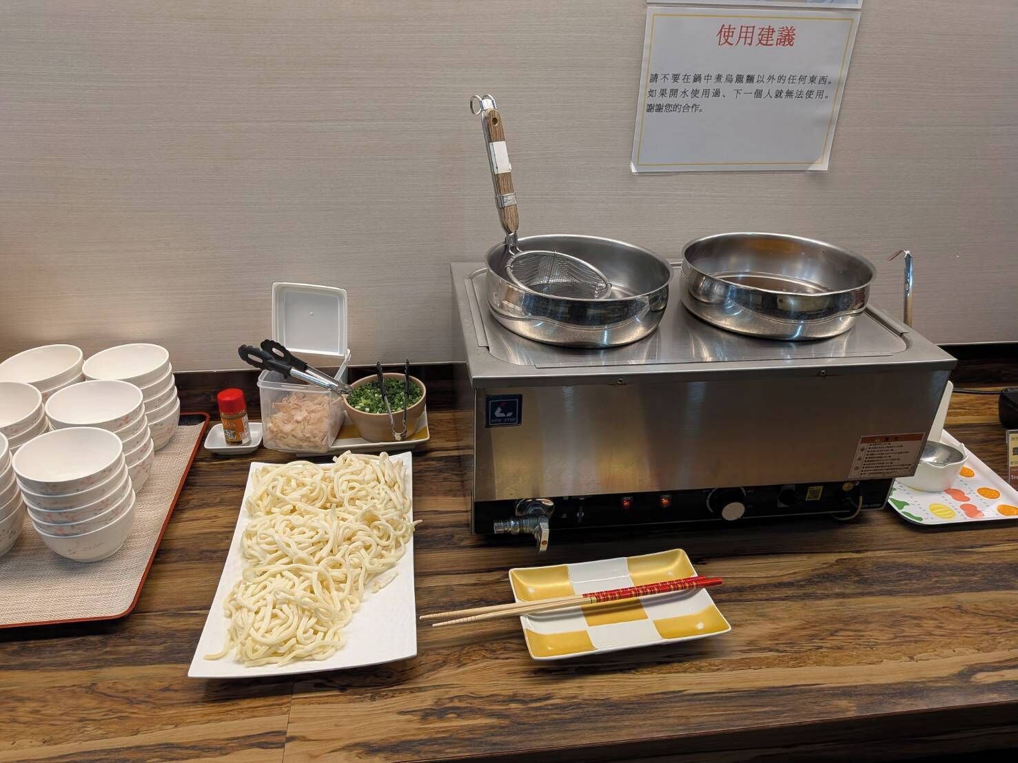 Ein Buffet mit Nudelgericht, Schüsseln und einem heißen Kochbereich.