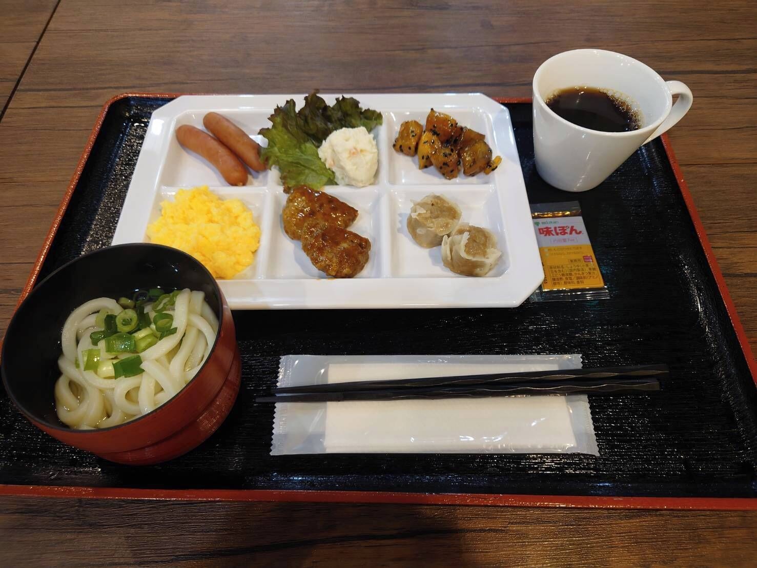 A meal tray with various dishes, a cup of tea, and chopsticks.