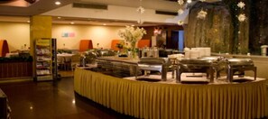 A buffet setup with multiple serving stations, a yellow tablecloth, and a decorative floral arrangement. - Dongshan Hotel, Guangzhou (Guangzhou)