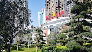 A hotel with a modern design, surrounded by well-maintained gardens and tall buildings in the background. - Dongshan Hotel, Guangzhou (Guangzhou)