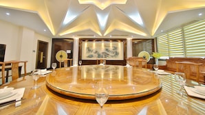 A round dining table with a central artwork, surrounded by wooden chairs and a sofa. - Dongshan Hotel, Guangzhou (Guangzhou)