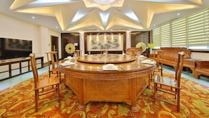 A round dining table with chairs, a chandelier, and a large painting on the wall. - Dongshan Hotel, Guangzhou (Guangzhou)