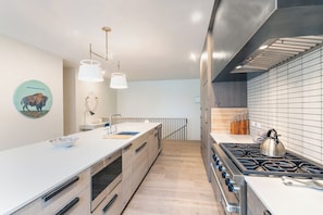 Una cocina moderna con una isla central, electrodomésticos de acero inoxidable y un salpicadero de azulejos.