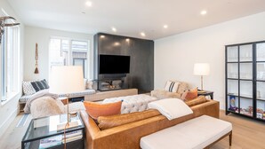 A modern living room with a sofa, a glass coffee table, a flat-screen TV, and a bookshelf. - SAN JUAN 103- Newly-Built, Masterfully Finished Jewel near Gondola, Shops, Resta (Telluride)