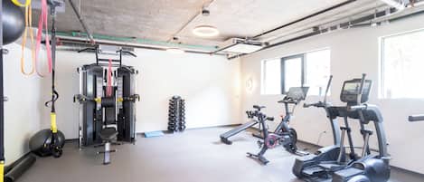Een fitnessruimte met diverse trainingsapparaten, waaronder een rack voor squats, gewichten en cardio-apparaten.