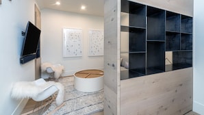 A modern living room with a flat-screen TV, white furry chair, round wooden table, and artwork on the wall. - SAN JUAN 103- Newly-Built, Masterfully Finished Jewel near Gondola, Shops, Resta (Telluride)