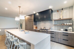 Cozinha moderna com uma ilha grande, banquetas, fogão a gás e backsplash de azulejos.