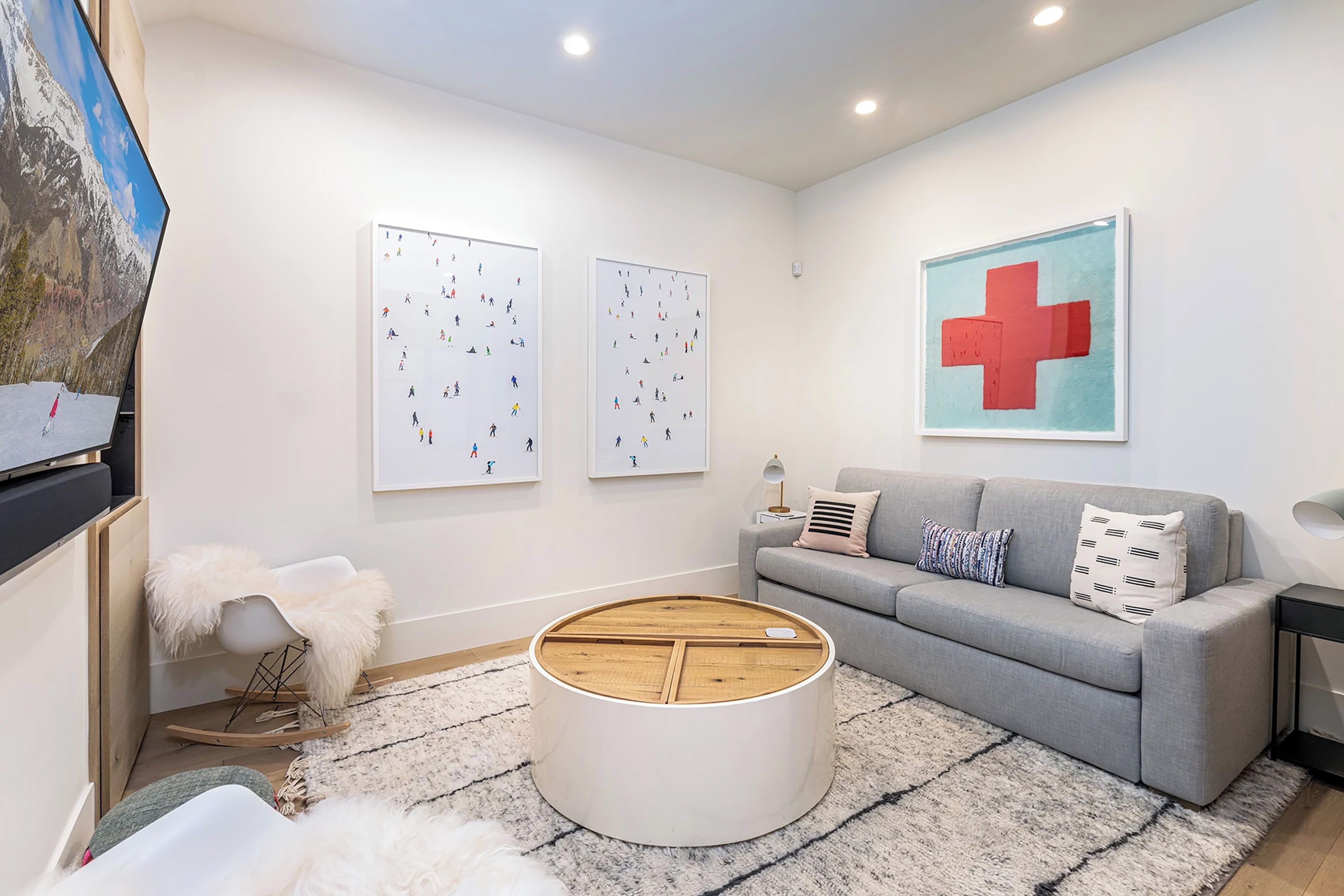 A modern living room with a grey sofa, a round coffee table, and two framed artworks on the wall.