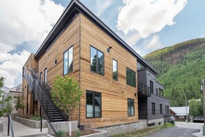 Un edificio moderno de dos pisos con fachada de madera y una escalera negra.