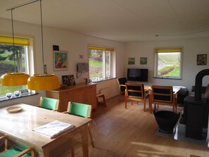 Une pièce comprenant une table à manger en bois, des chaises, un téléviseur et une cheminée.