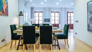 A dining area with a wooden table, green upholstered chairs, and a modern pendant light. - Deluxe Penthouse Giralda Views, 3Bd 2Bt, 7 people, Parking optional (Sevilla)