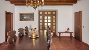 Un comedor con una mesa de madera, sillas, una araña, un cuadro y una puerta con paneles de vidrio.