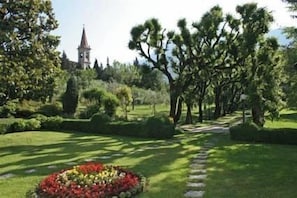 A well-maintained garden with a stone pathway, neatly trimmed hedges, and a variety of flowering plants.