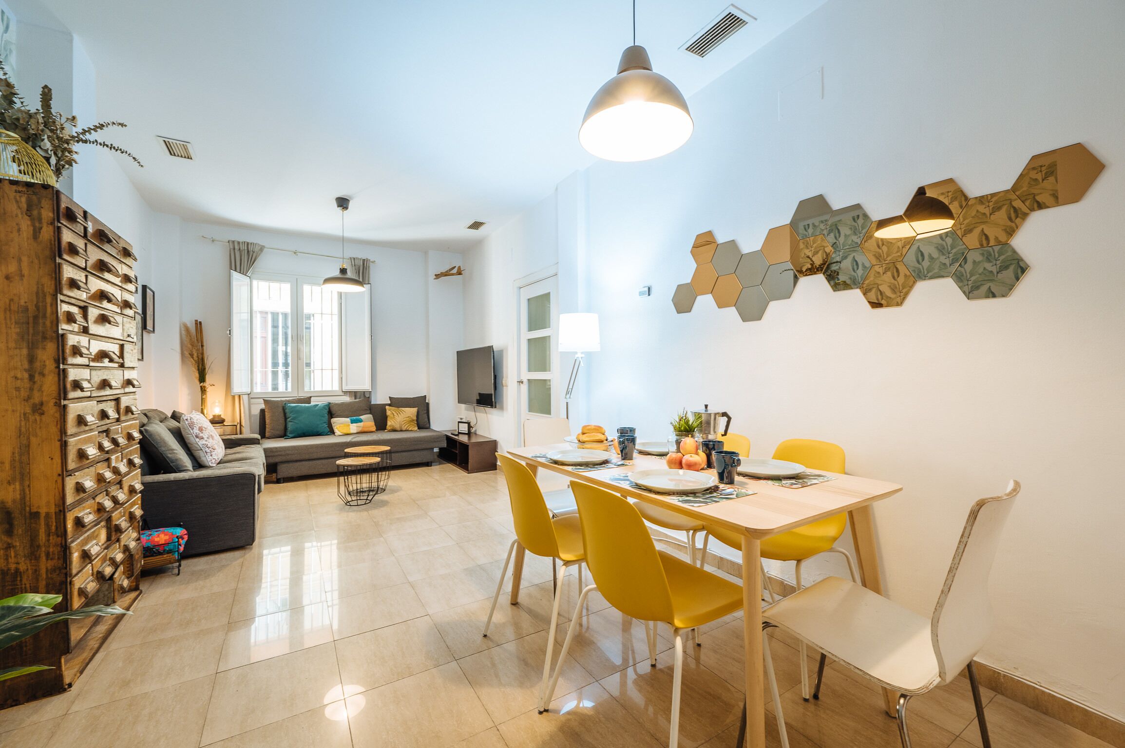 Een moderne woonkamer met een eethoek, met een zithoek, een houten kast en een tafel met gele stoelen.