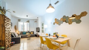 Un salon moderne avec un coin repas, comprenant un ensemble de canapés, un meuble en bois et une table avec des chaises jaunes.