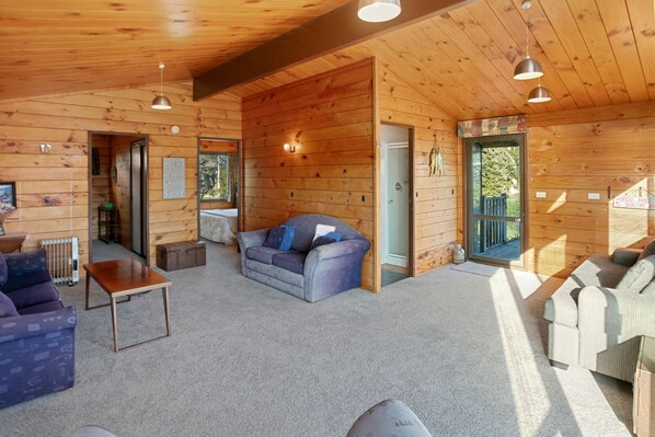 A cozy log cabin interior with a sofa, a coffee table, and a fireplace.