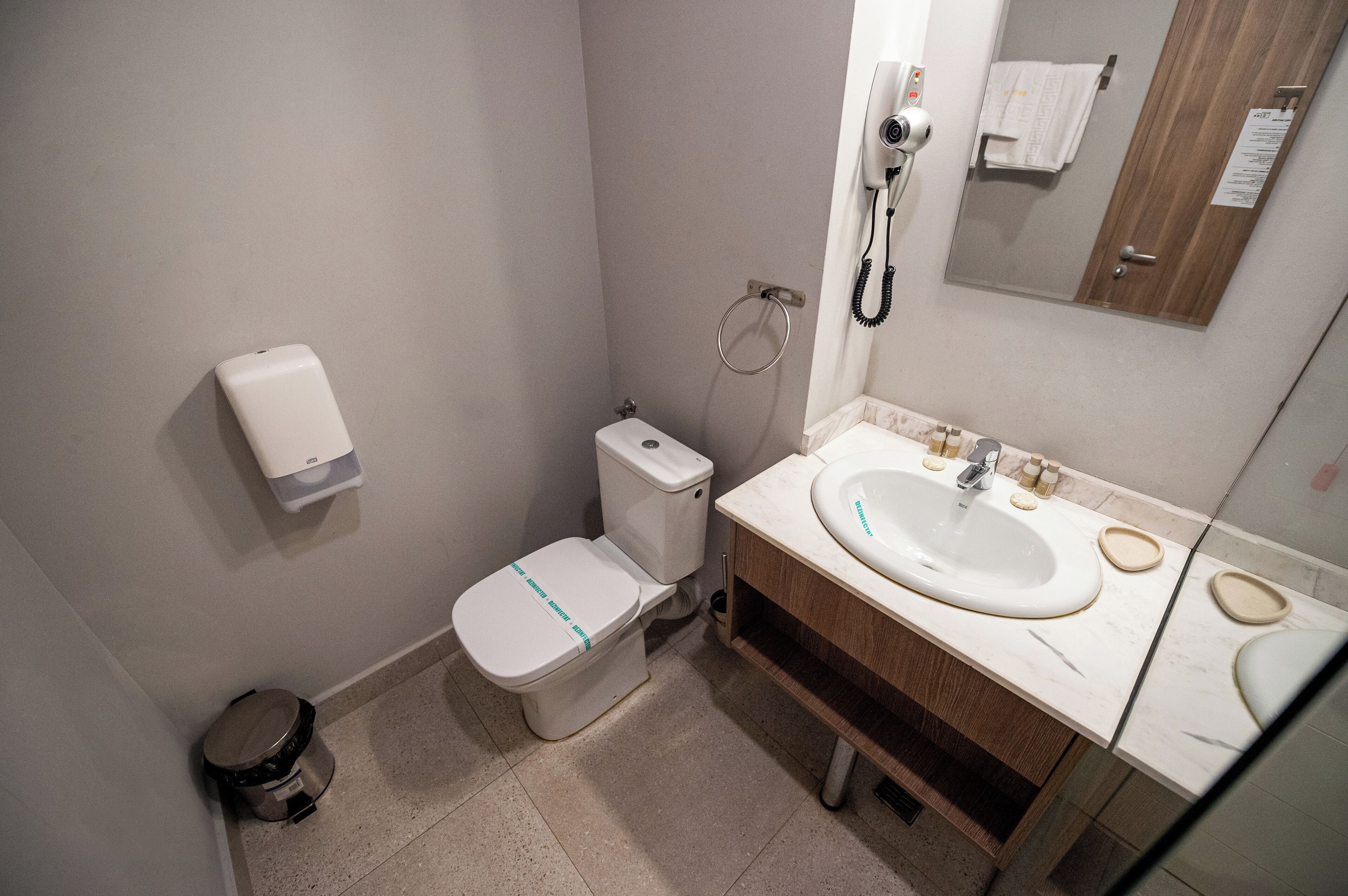A small bathroom with a toilet, bidet, sink, and mirror.