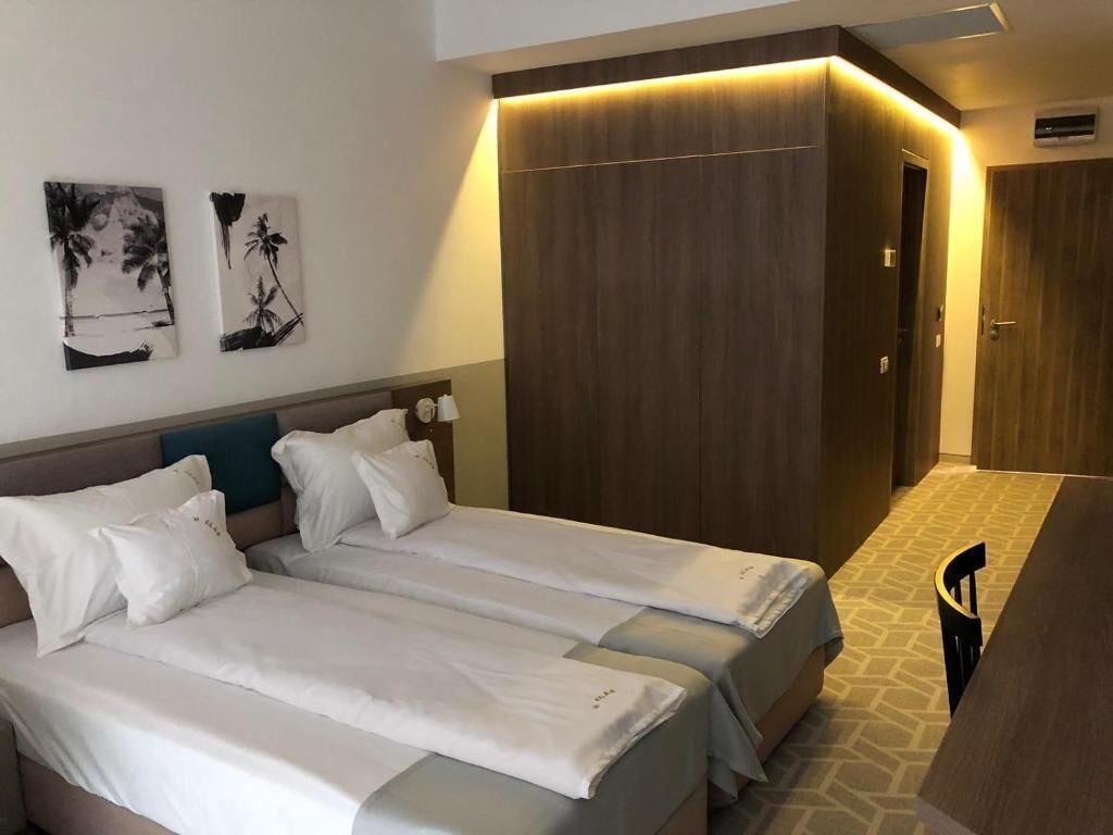 A hotel room with two beds, a wardrobe, and a desk.