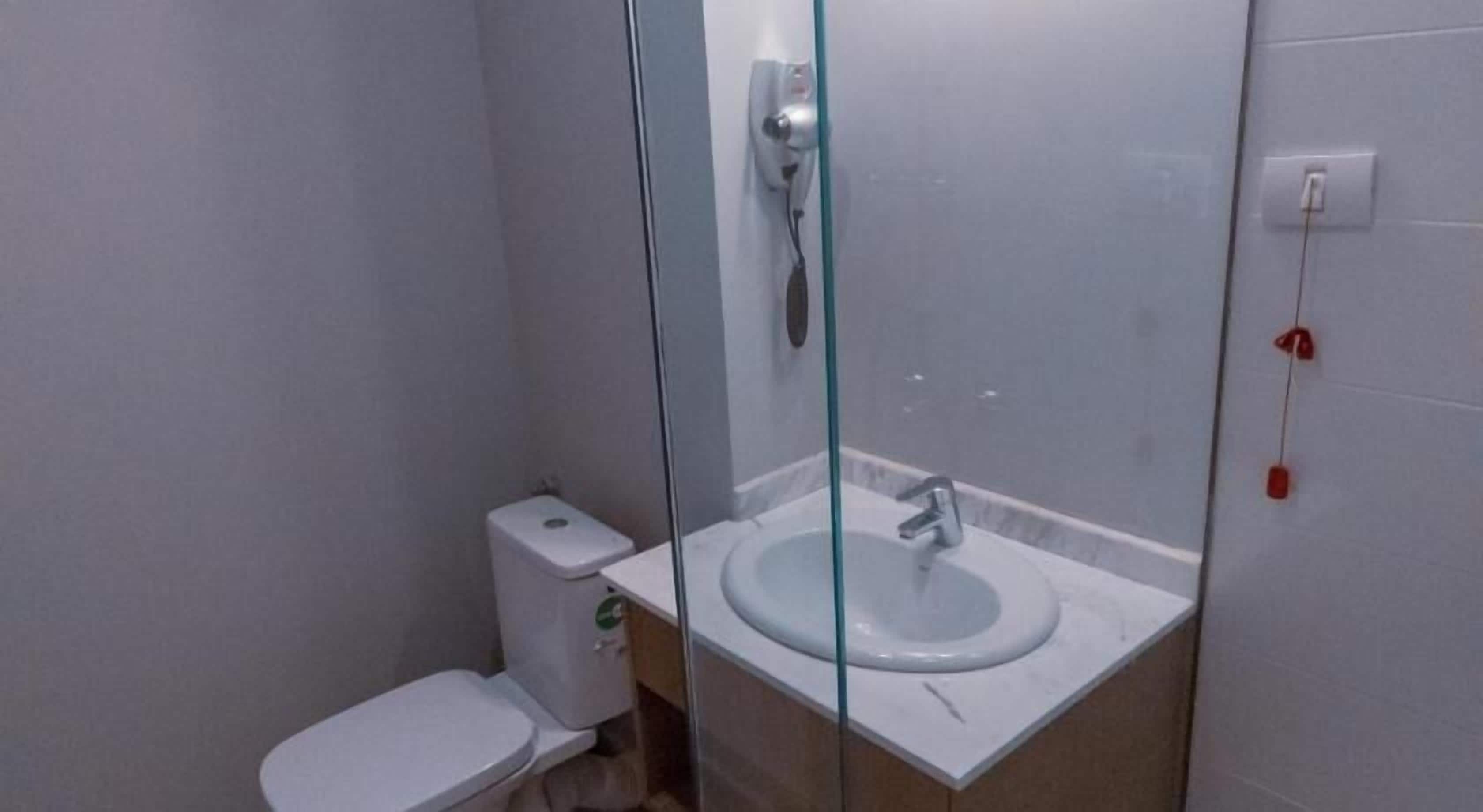A small bathroom with a toilet, a glass-enclosed sink, and a shower.