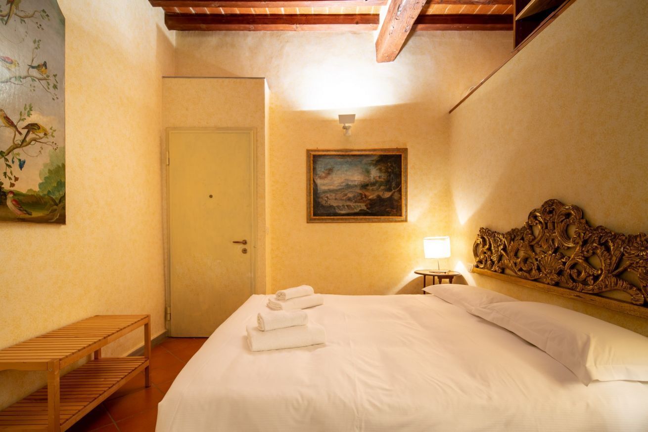 Una habitación de hotel con una cama, un cuadro, un banco de madera y una puerta.